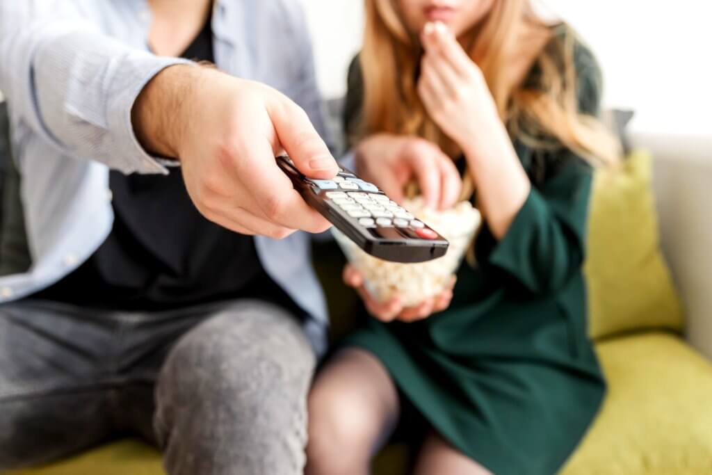 couple holding remote and watching a movie