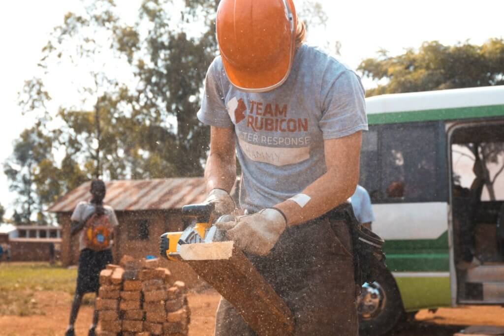 man cutting wood to make house for the underprivileged 